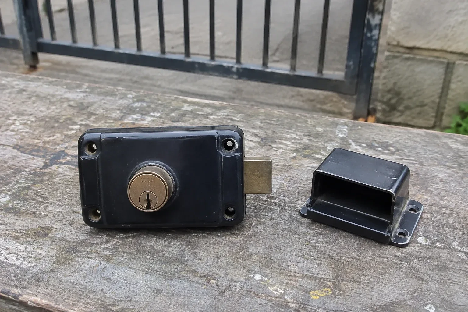 Detached rim gate lock and separate box keeper on an outdoor workbench. — Gate & Building Entry Locks, Halton Hills
